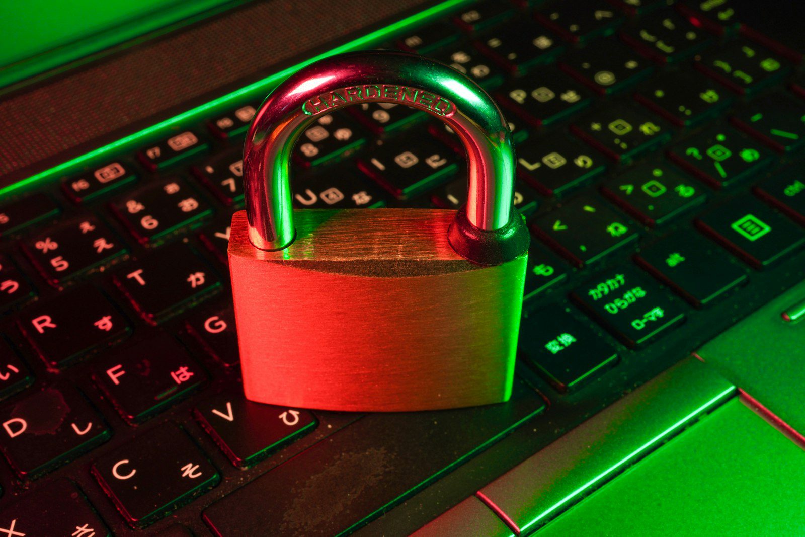 Padlock resting on a laptop keyboard lit in red and green, representing cyber security
